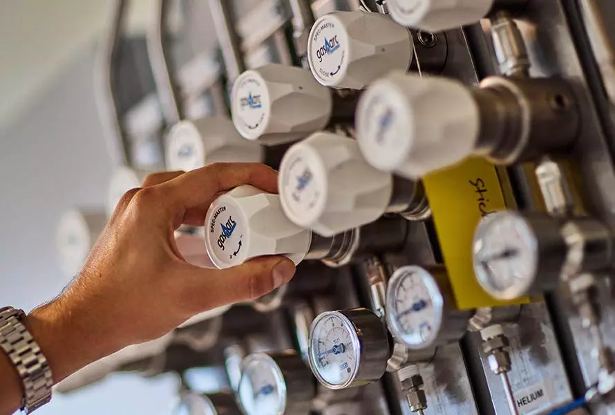 photo of researcher hand in catalysis hub labs at gas pipes